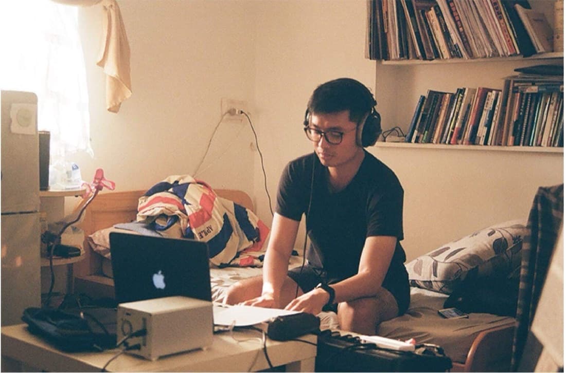 Alex wearing headphones, working at a desk with a laptop and audio gear